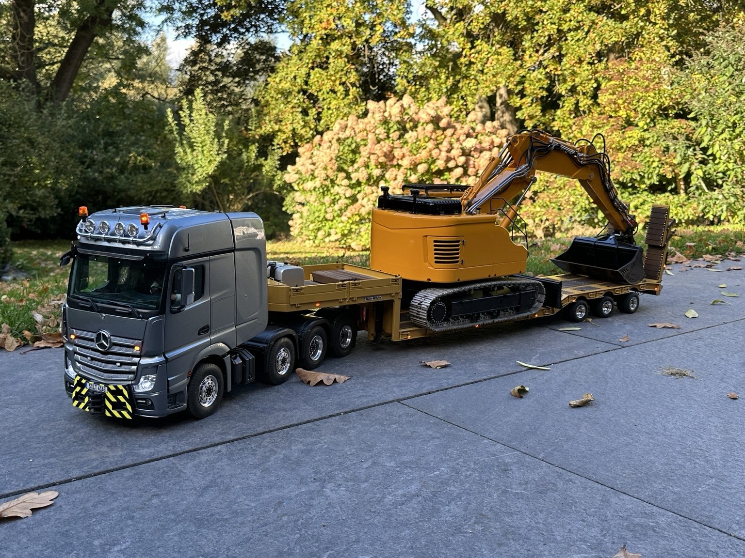 Grauer Actros mit Tieflader und Bagger